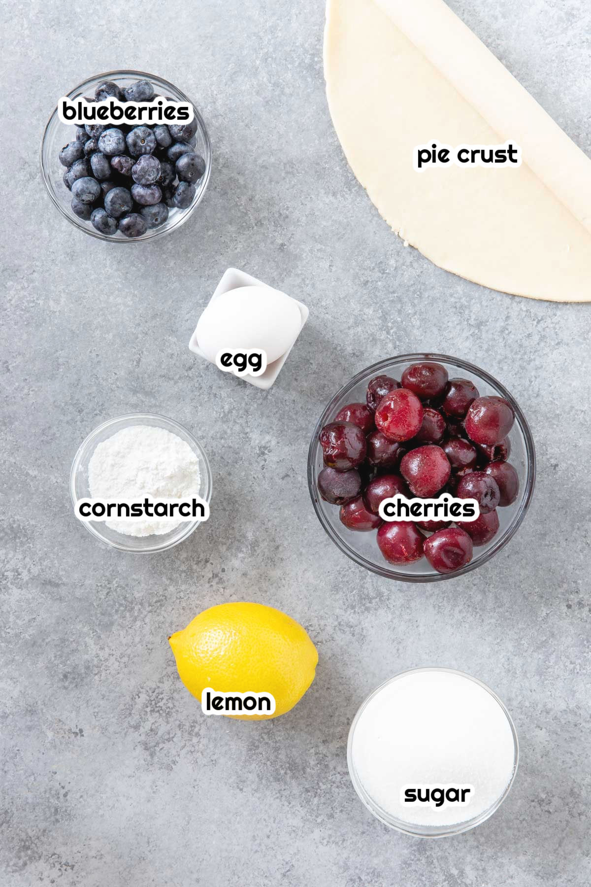 blueberries, pie curst, egg, cornstarch, cherries, lemon, sugar in bowls