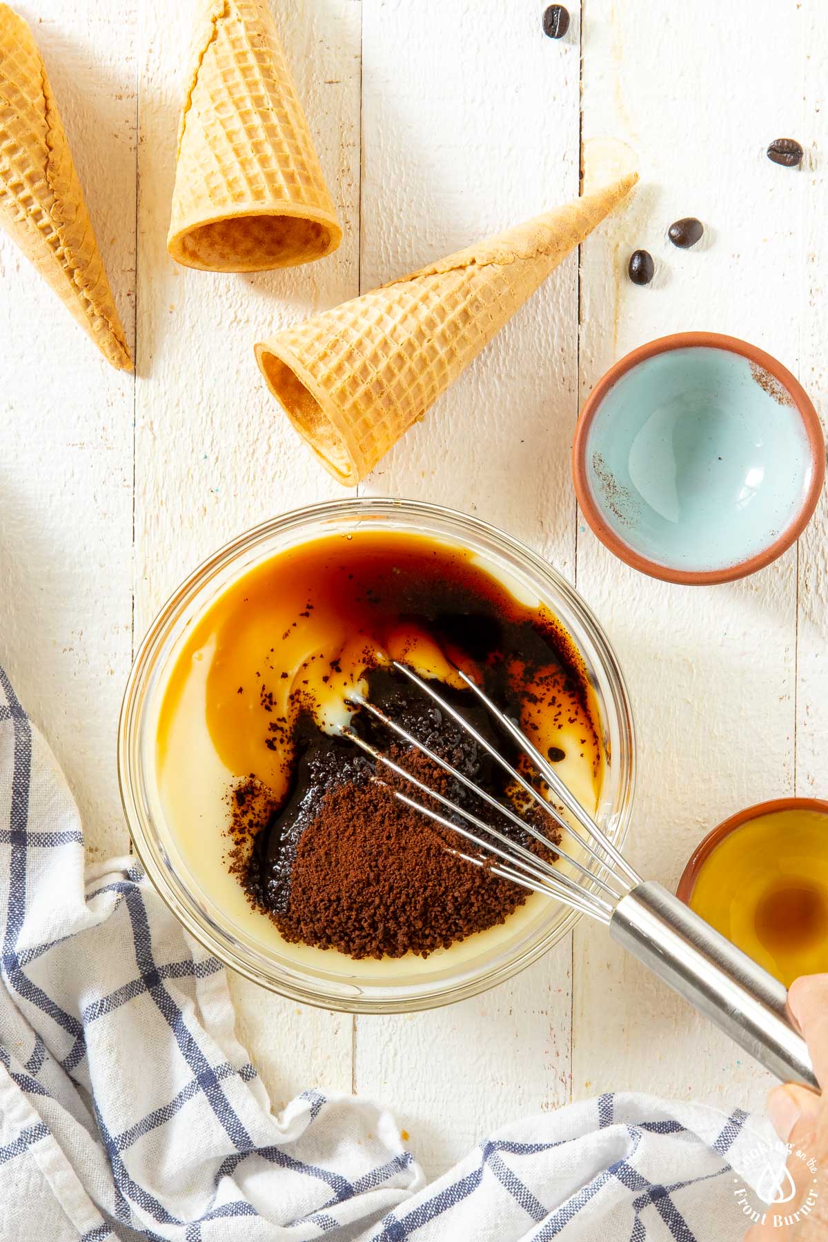 clear bowl with sweetened milk, coffee granuales and kahlua and a whisk