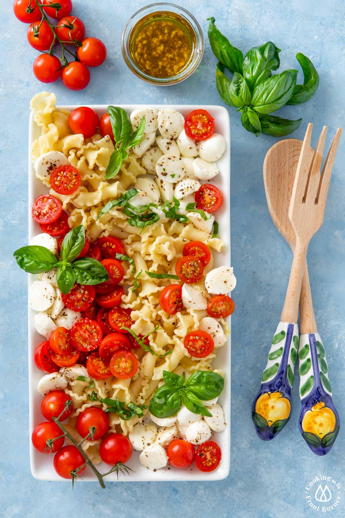 white platter with pasta, tomatoes, basil and mozzarella balls
