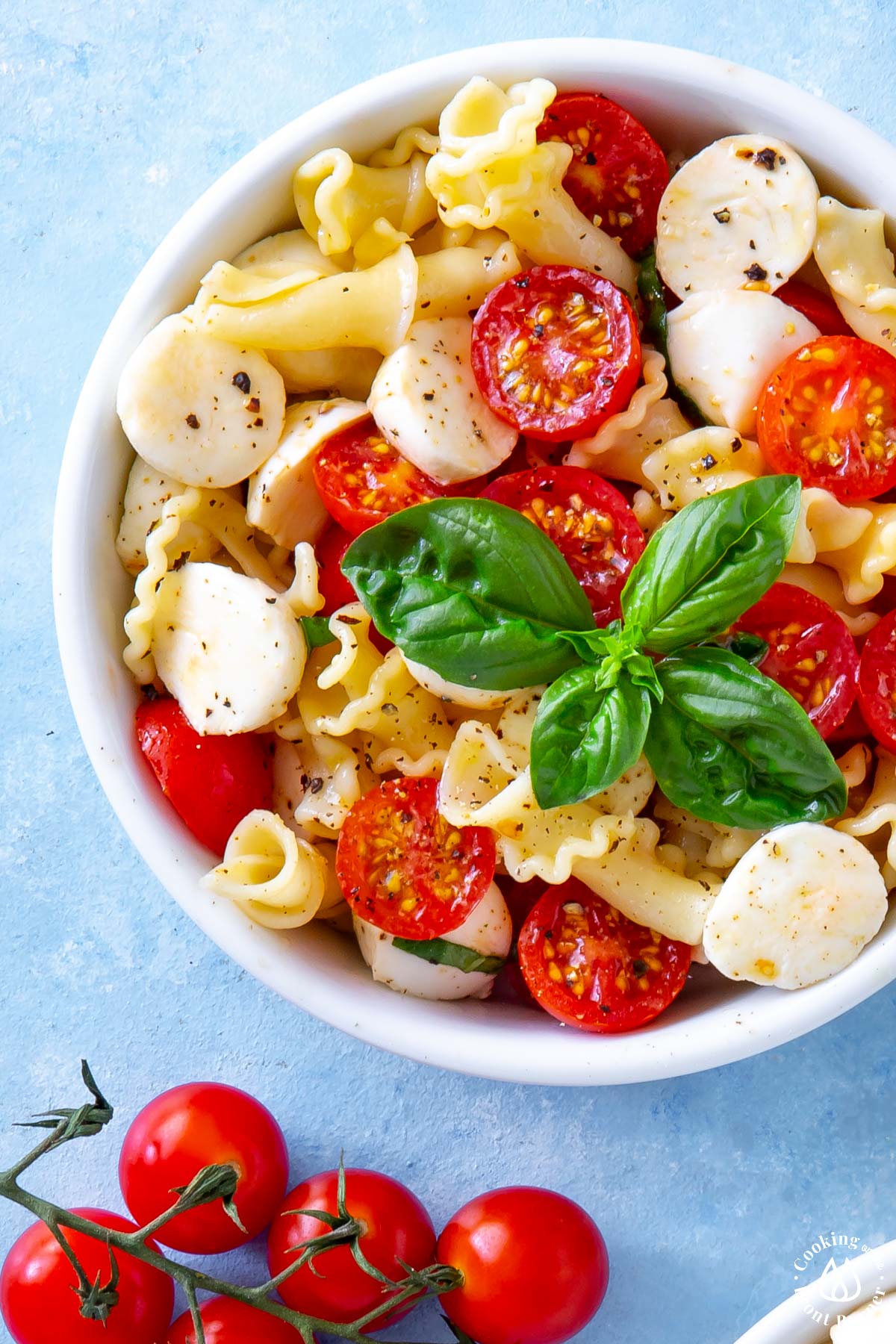 white bowl with caprese pasta salad topped with fresh basil