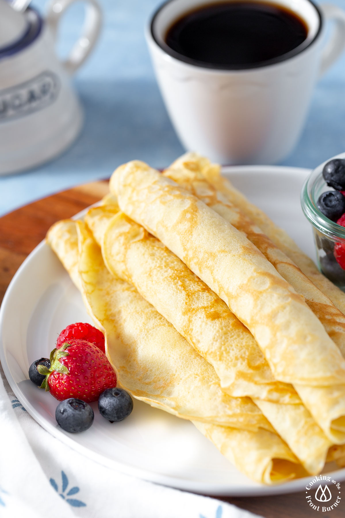 rolled crepes on a white plate with a side of berries
