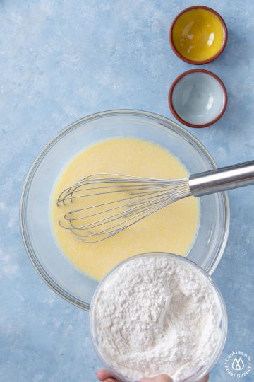 flour being poured into egg milk batter