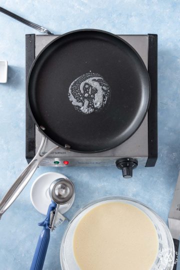 crepe skillet on a burner with melted butter