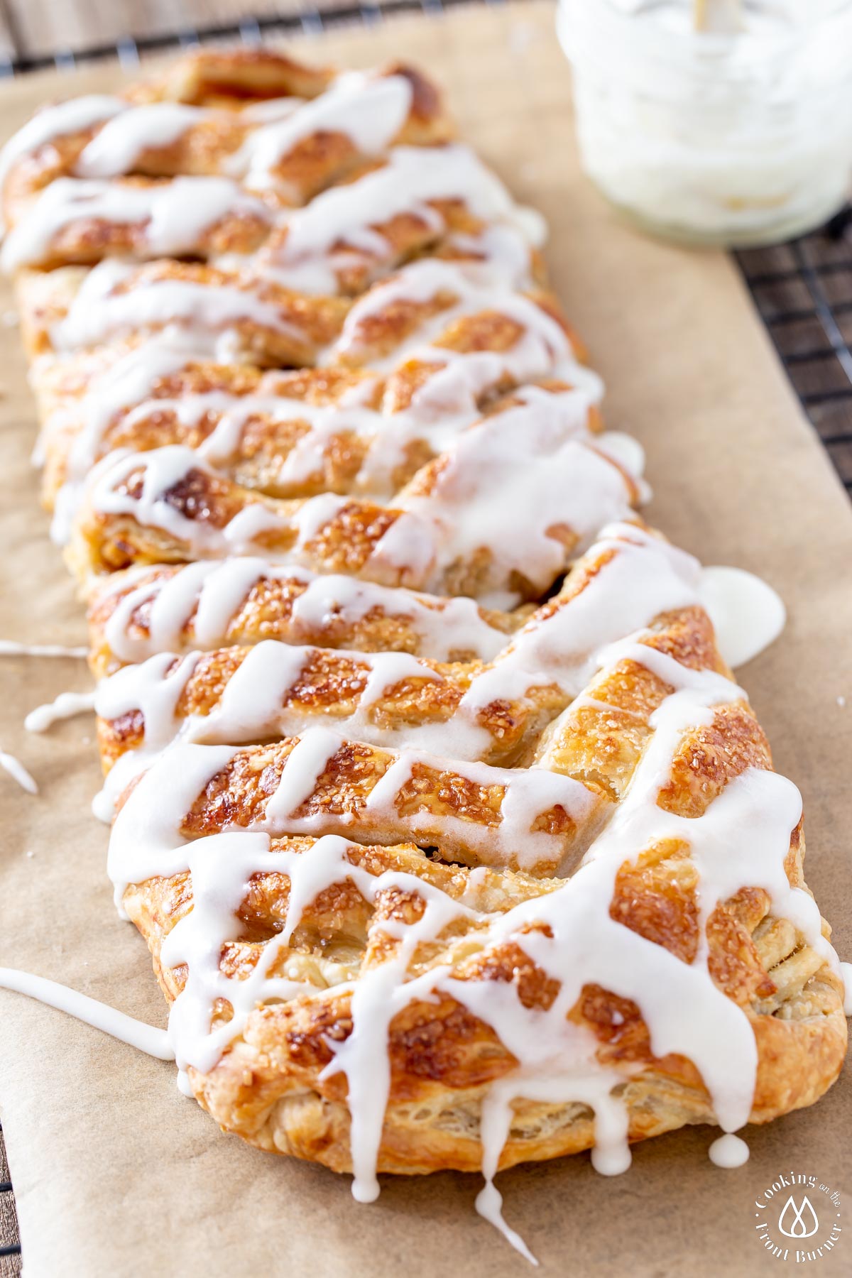 baked apple puff pastry strudel on parchment drizzled vanilla glaze