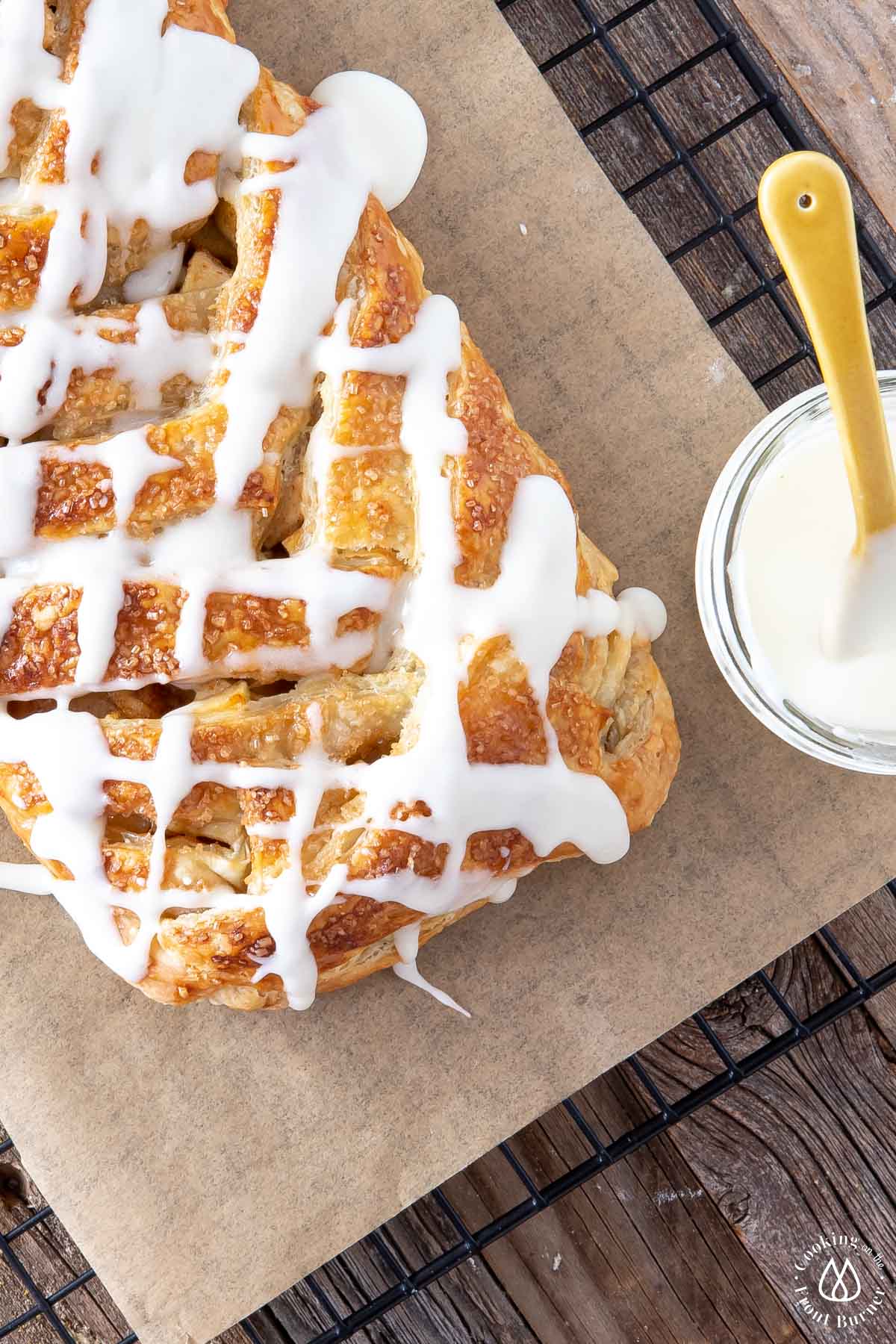 apple strudel with vanilla glaze on a cooling rack and parchment paper